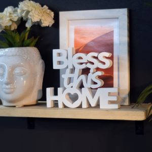 An aesthetic table decor piece with the words "Bless This Home" sitting on an office desk.