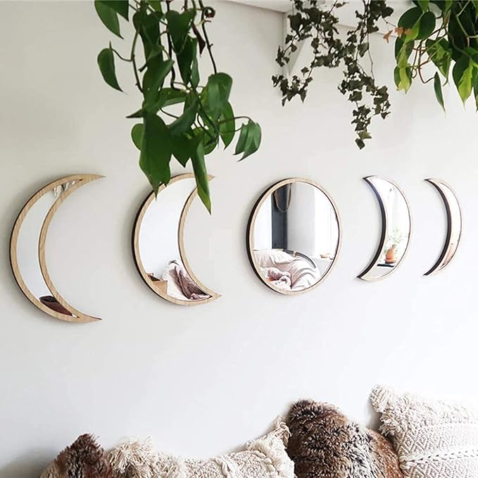 A 5-piece set of wooden and acrylic moon phase wall decor hanging horizontally above a bed